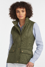 An image of a female model wearing the Barbour Otterburn Gilet in the colour Olive.