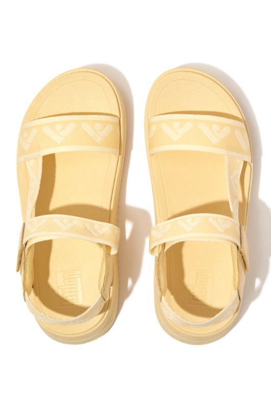 Fitflop Surff Webbing Back Strap Sandals. A pair of yellow chunky sandals with wide strap featuring an arrow print design and microwobbleboard cushioned sole.