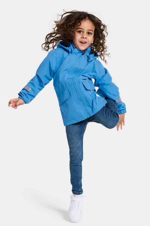 Didriksons Norma Jacket. A windproof kids jacket with a breathable design, a detachable hood, pockets, reflective details on the sleeves and a chin guard