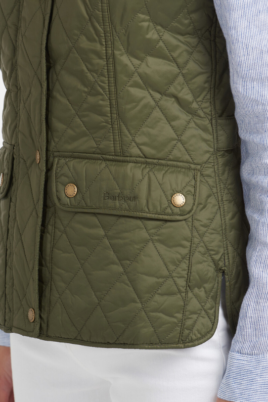 An image of a female model wearing the Barbour Otterburn Gilet in the colour Olive.